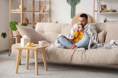 Evde limon çayıyla hapşıran genç adam.