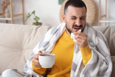 Evde hapşıran limonlu çaylı genç adam.