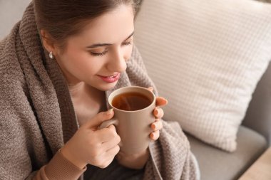 Ekoseli genç bir kadın evde limonlu çay içiyor, yakın plan.