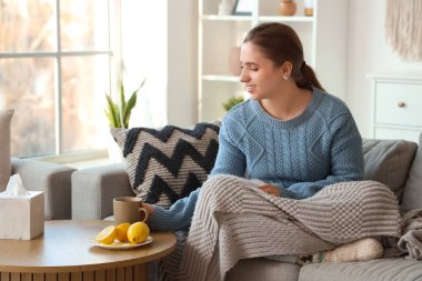 Gülümseyen genç bir kadın evdeki masadan bir bardak limon çayı alıyor.