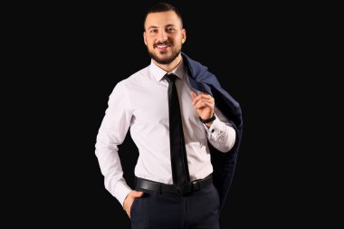 Siyah arka planda kravatı olan takım elbiseli genç işadamı.