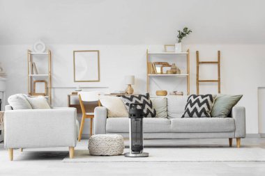 Oturma odasının içinde kanepeler, puf ve elektrikli ısıtıcı var.