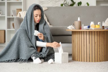 Ekose kumaşlı genç bir kadın. Evdeki kutudan mendil alıyor.