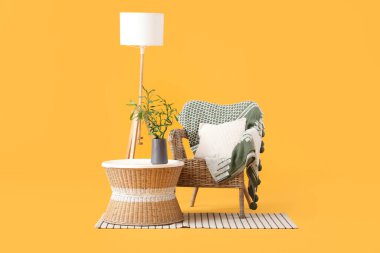 Vazoda bambu saplı masa, koltuk, lamba ve sarı arka planda halı.