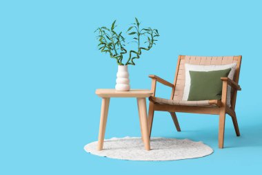 Vazoda bambu saplı masa, mavi arka planda koltuk ve halı.