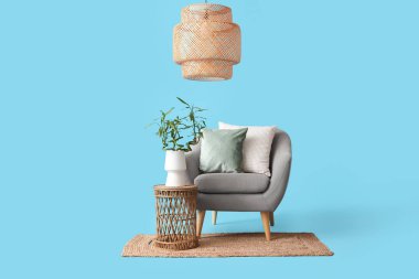 Vazoda bambu saplı masa, koltuk, halı ve lamba mavi arka planda.