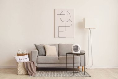 Masasında kanepe, lamba ve elektrikli vantilatör olan bir oturma odası.