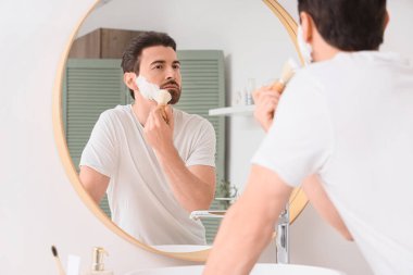 Yakışıklı bir adamın banyoda aynanın yanında tıraş köpüğü sürdüğü bir sabah.