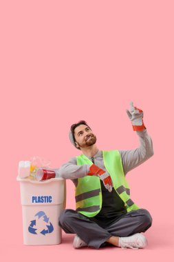 Çöp tenekeli erkek leş yiyici pembe arka plandaki bir şeyi işaret ediyor.