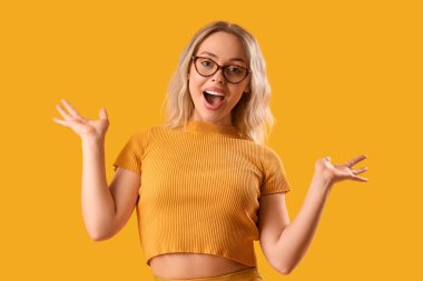 Turuncu arka planda gözlüklü mutlu genç kadın.