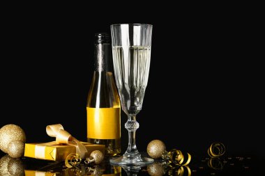 Şenlikli yeni yıl partisi kompozisyonu. Siyah arka planda şişe ve bir bardak şarap..