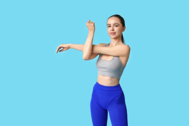 Genç bayan antrenör mavi arka planda ısınıyor.