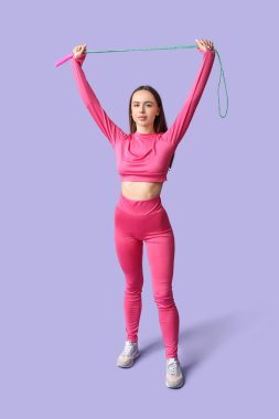 Leylak arka planında ip atlama egzersizi yapan genç bayan antrenör.