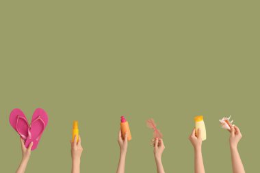 Yeşil arka planda deniz kabuğu, parmak arası terlik ve güneş kremi olan bir sürü el.