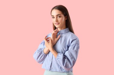 Pembe arka planda poz veren resmi kıyafetli güzel, genç bir kadın.