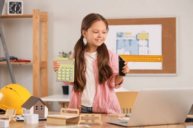 Evde dizüstü bilgisayarında hesap makinesi ve kare cetvelli ev projesiyle sevimli küçük bir mimar.