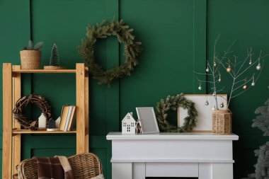 Şömine, raf ünitesi ve yeşil duvarın yanındaki Noel dekoru.