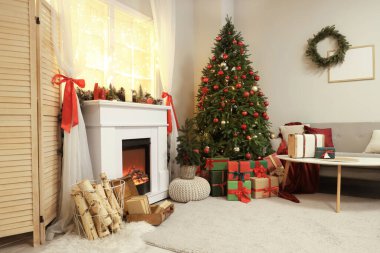 Güzel şöminesi, kanepesi, masası ve süslü Noel ağacı olan şık bir oturma odası.