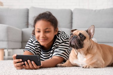 Fransız bulldoglu tatlı Afro-Amerikalı kız oturma odasında selfie çekiyor.