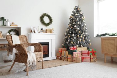 İçinde şömine, Noel ağacı ve hediyeler olan oturma odası.