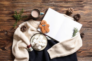 Marşmelovlu kompozisyon, boş kitap, ahşap arka planda kazak ve çam kozalakları