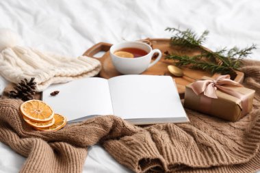 Çayla kitap, Noel hediyesi ve sıcak tutacak elbiseler, yakın plan.