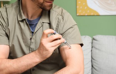 Şeker hastası genç adam evde tükenmez kalem kullanıyor, yakın plan.