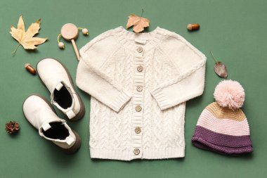 Yeşil arka planda şık çocuk kıyafetleri, ayakkabıları ve düşmüş yaprakları olan kompozisyon