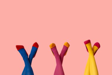 Tayt giymiş kadın bacakları ve pembe arka planda yüksek topuklu şık ayakkabılar.