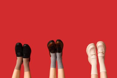 Kırmızı arka planda şık ayakkabılı kadın bacakları