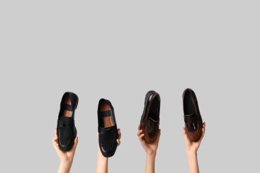 Gri arka planda şık ayakkabıları olan kadın elleri.