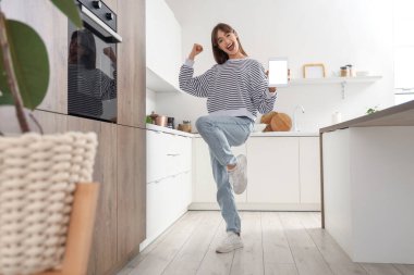 Mutfakta boş tablet bilgisayarı olan mutlu genç bir kadın.