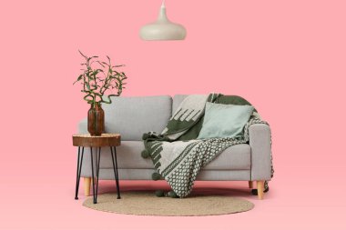 Vazoda, kanepede ve pembe arka planda bambu saplı masa.