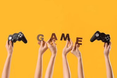 Kelime oyunu yapan kadın eller ve sarı arka planda joystickler.