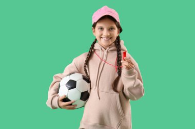 Yeşil arka planda ıslık çalan ve futbol topu olan sevimli bir antrenör.