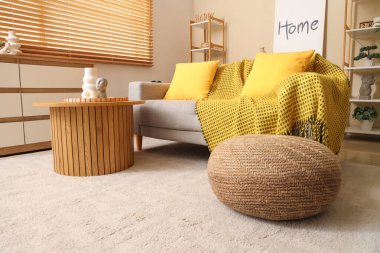 Sarı yastıklı ve kanepede ekose kumaşlı rahat bir oturma odası.