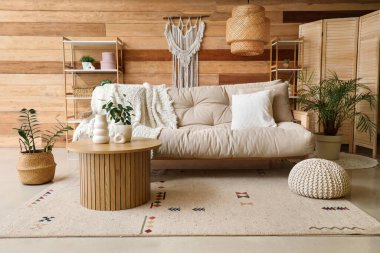 İçinde bej kanepe, masa ve raf üniteleri olan rahat bir oturma odası.