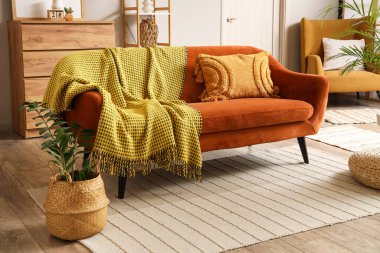 Oturma odasında minderli ve sıcak ekose kaplı kırmızı kanepe.