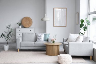 Gri kanepeler, masa ve bitkilerle aydınlık oturma odasının içinde.