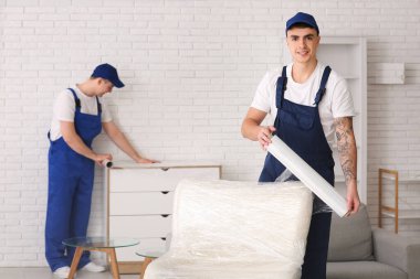 Erkek yükleyici odada streç film ile koltuğu sarıyor