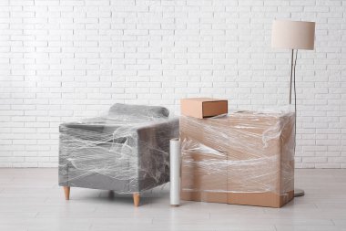 Taşınırken odada streç film olan paketlenmiş koltuk ve karton kutular