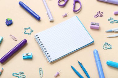 Turuncu arka planda farklı kırtasiye malzemesi içeren defter