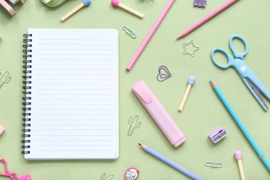 Yeşil arka planda farklı kırtasiye malzemesi içeren defter