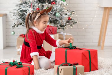 Noel Baba kostümlü, Noel arifesinde evde hediye kutularıyla sevimli küçük bir kız.