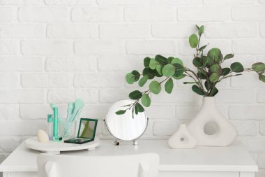 Okaliptüslü vazo, makyaj malzemeleri ve soyunma odasındaki ayna.