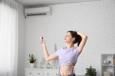 Evinde klima uzaktan kumandalı güzel bir kadın.