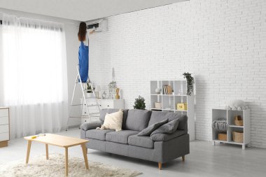 Kadın teknisyen evde klima tamir ediyor.