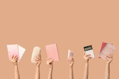 Bej arka planda farklı kırtasiyeye sahip kadın elleri