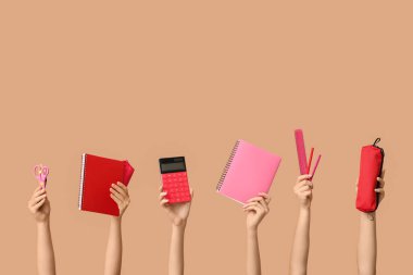 Bej arka planda farklı kırtasiyeye sahip kadın elleri