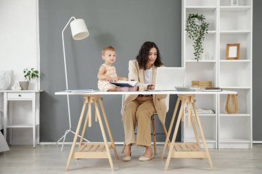 Bilgisayarlı çalışan anne ve evdeki küçük bebeği.